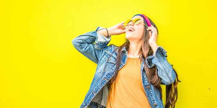 Smiling woman standing against yellow wall
