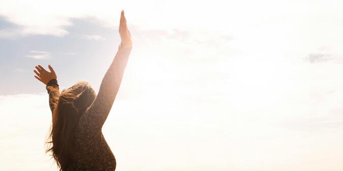 Photograph of a woman with her hands raised