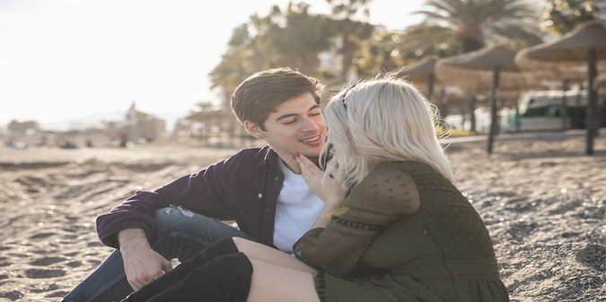 older woman and younger man sitting on the beach